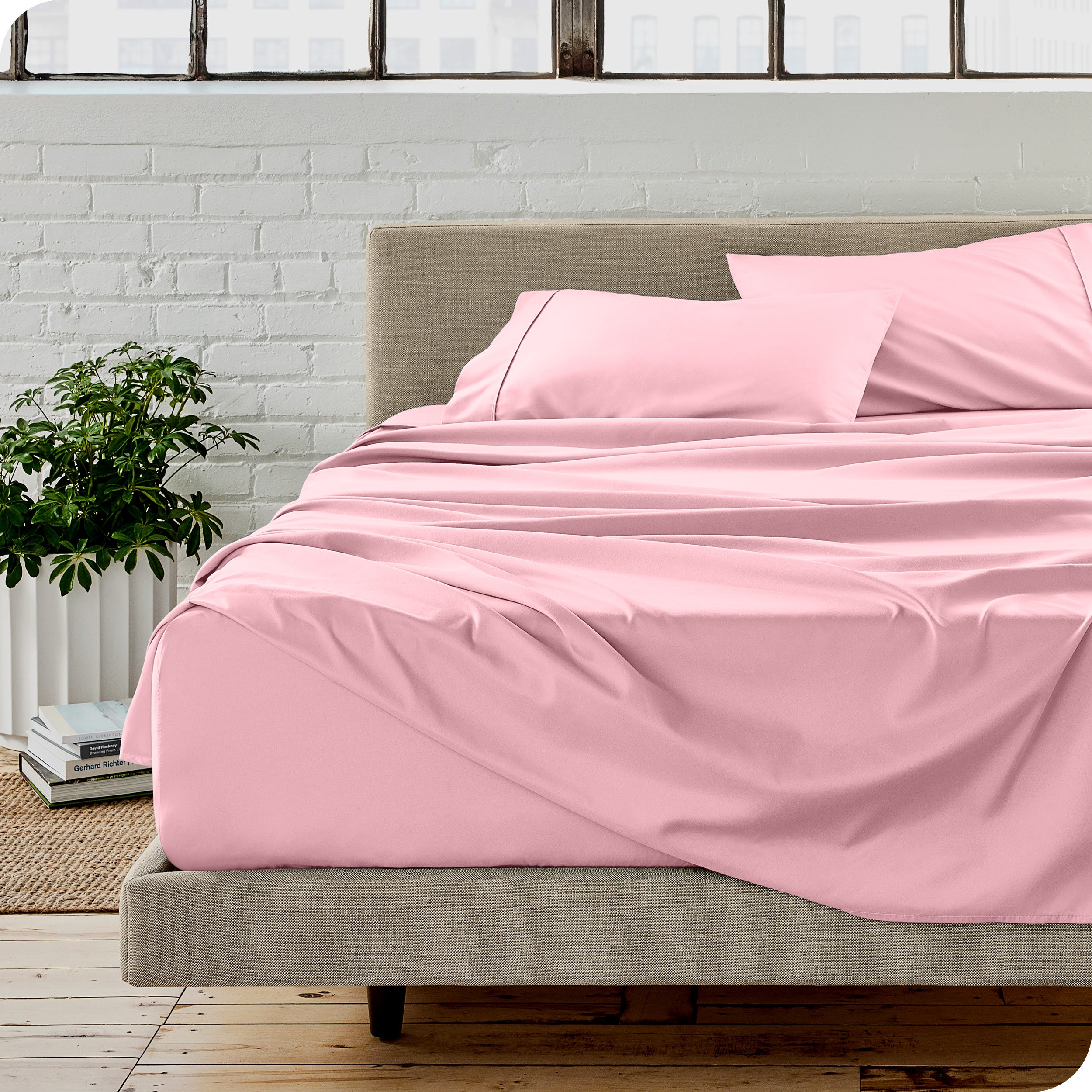 Microfiber sheets on a bed with a brick wall behind it