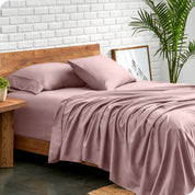 Microfiber sheets and matching pillowcases on a bed next to a large plant