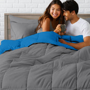 A couple sitting in a bed made with a reversible comforter and sheet set