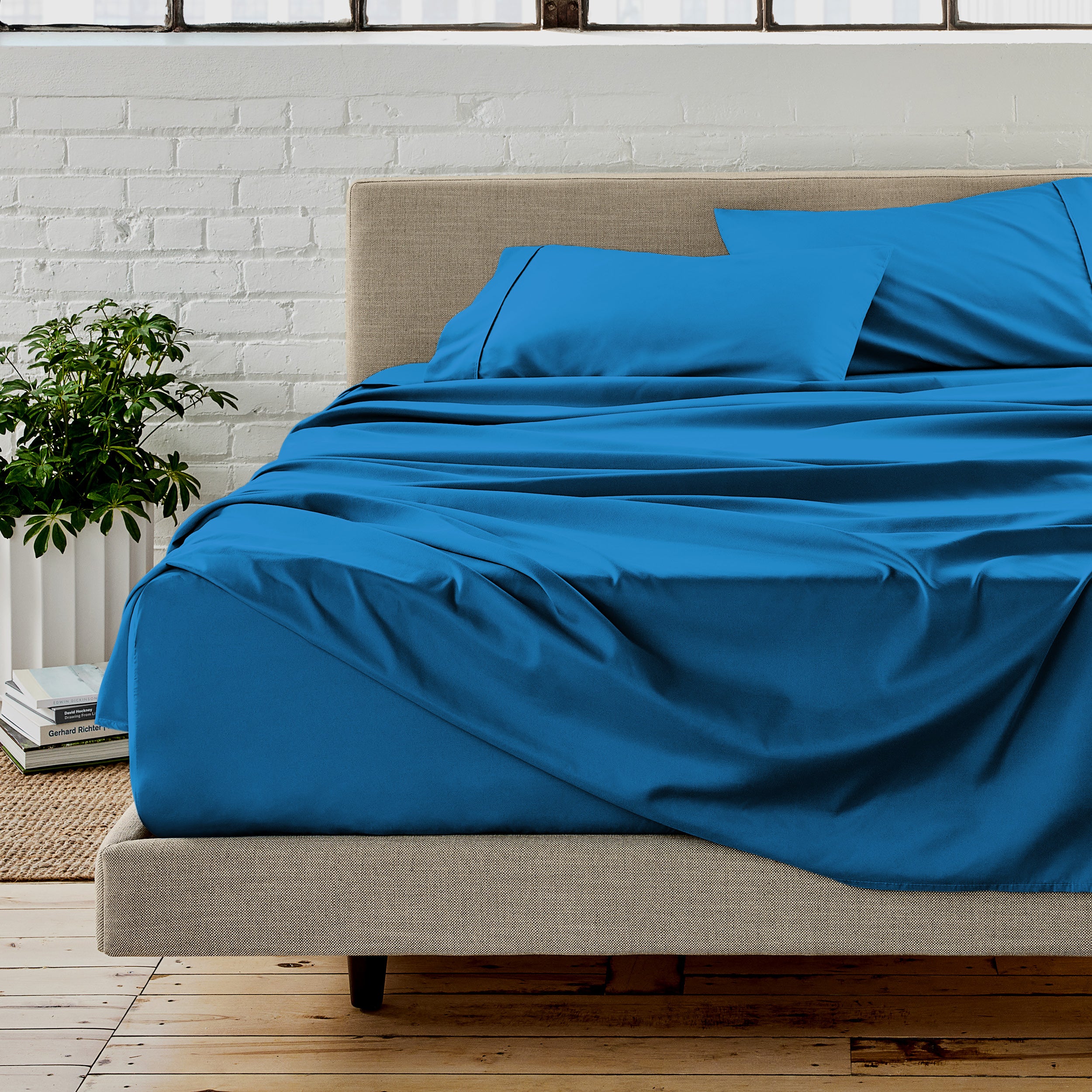 The sheet set with the matched same color pillowcases putting over the bed in a modern room.