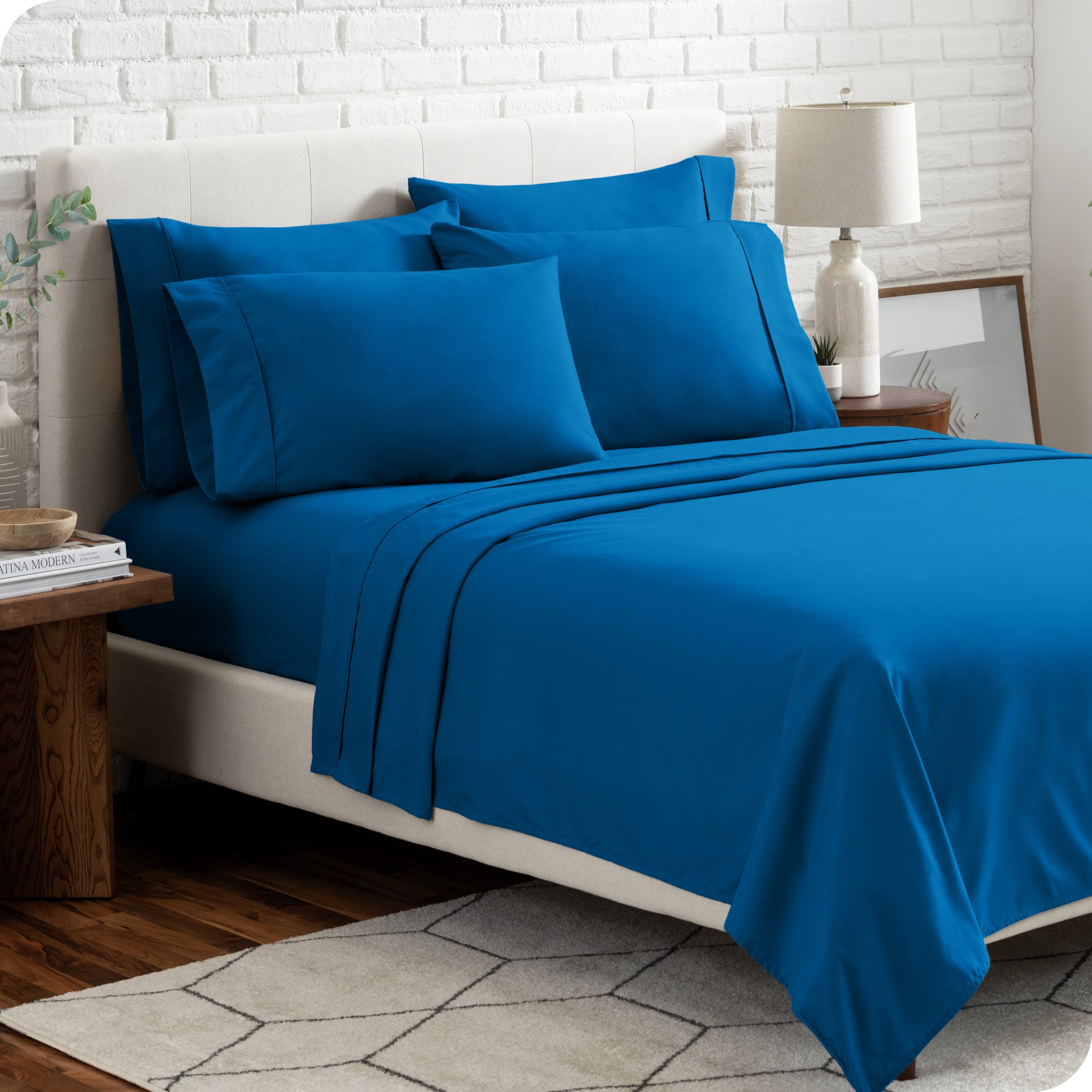 A bedroom setting with a bed made with the microfiber bed sheets and four pillows.