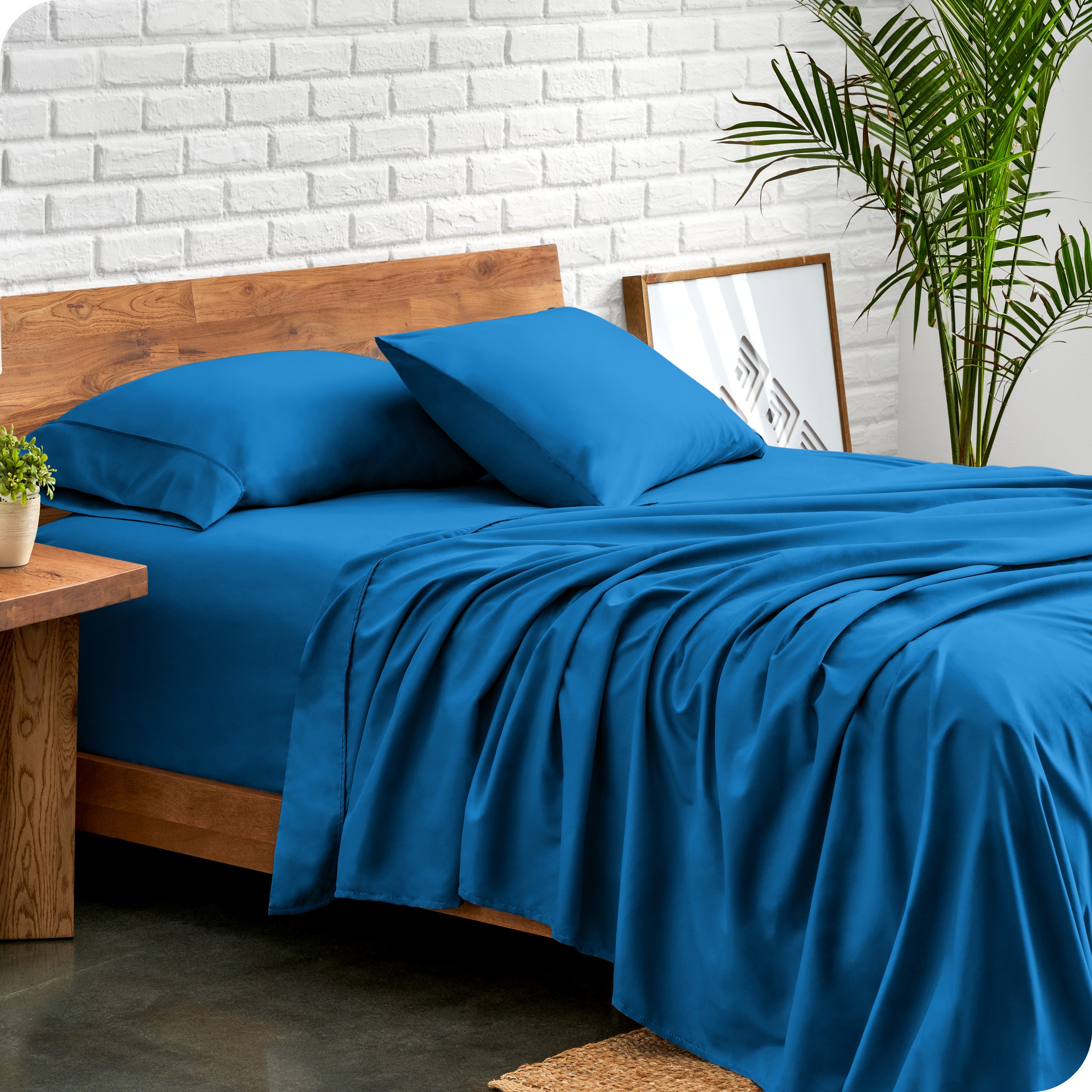 Microfiber sheets and matching pillowcases on a bed next to a large plant