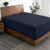 A wide corner view of a modern bed made with a microfiber fitted sheet on the mattress.