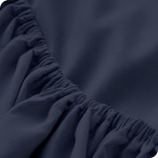 A modern bed with a fitted microfiber sheet on it