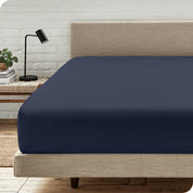 Closer end of the bed with a microfiber fitted sheet on the mattress.