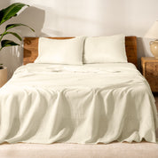 Bed with linen bedding and wooden headboard in a bedroom setting