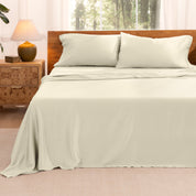 TENCEL™ sheet set on a bed with the flat sheet loosely draped over the top. The mattress is on a wooden bed frame.