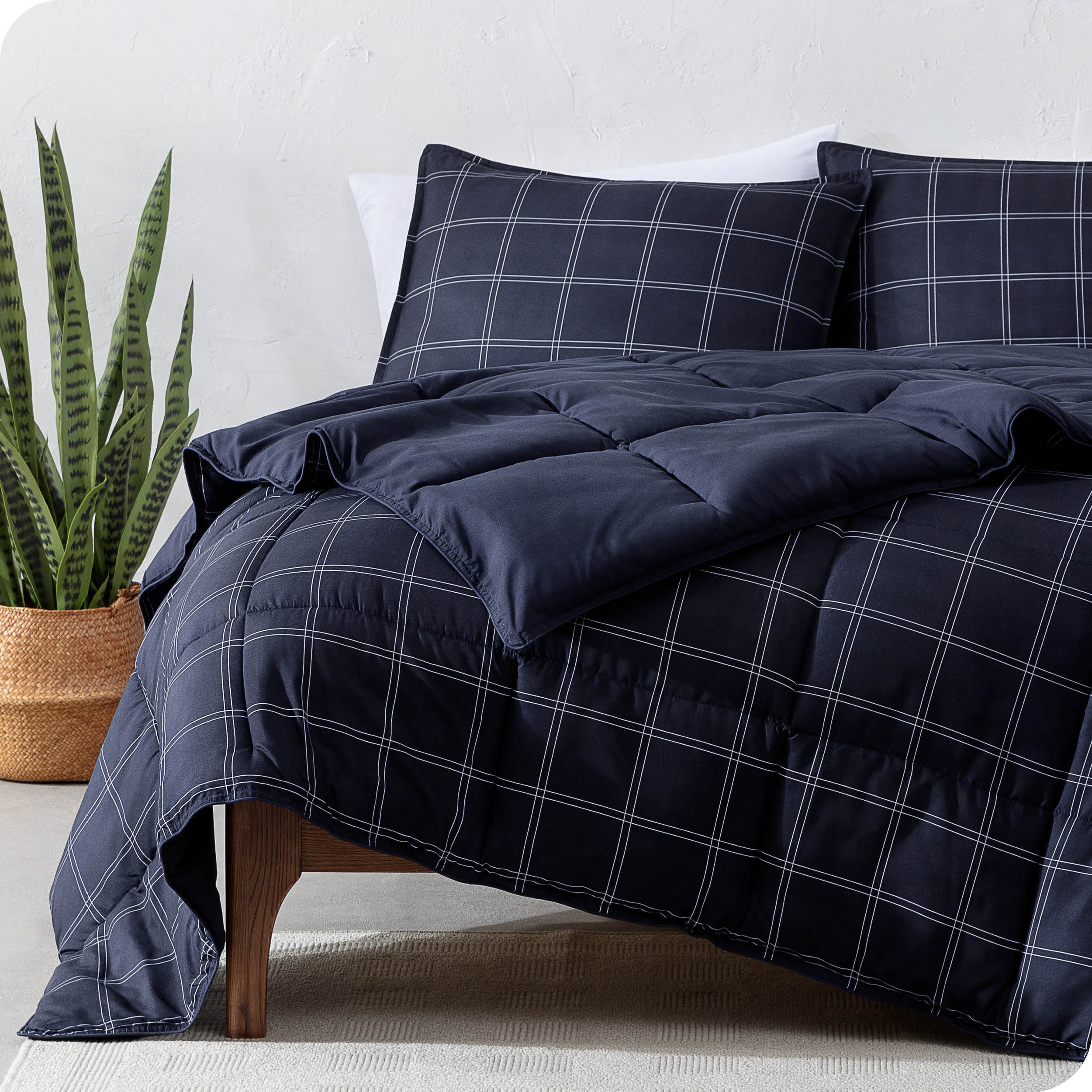 Printed comforter set on a bed next to a large plant
