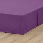A box spring with a bed skirt on it