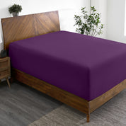 A wide corner view of a modern bed made with a microfiber fitted sheet on the mattress.