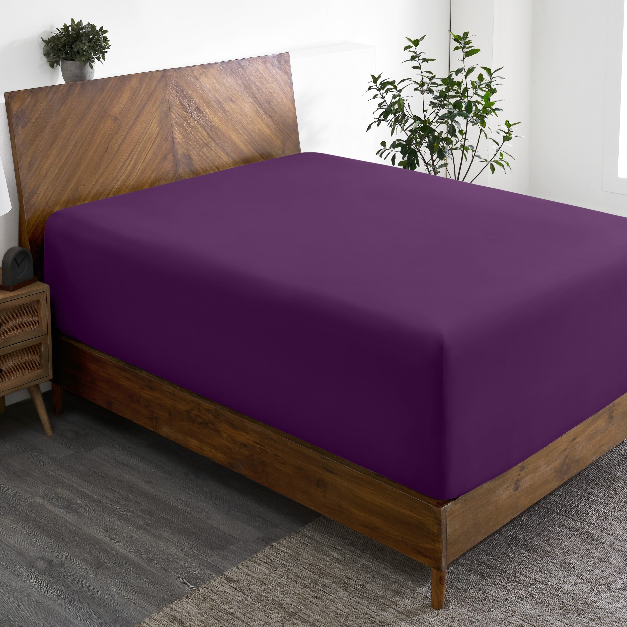 A wide corner view of a modern bed made with a microfiber fitted sheet on the mattress.