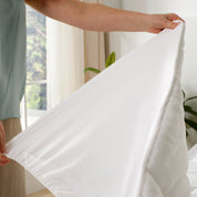 A hand is showing the side layer of the reversible mattress pad.