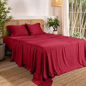 Bamboo sheets on a bed in a bedroom with plants and a window.