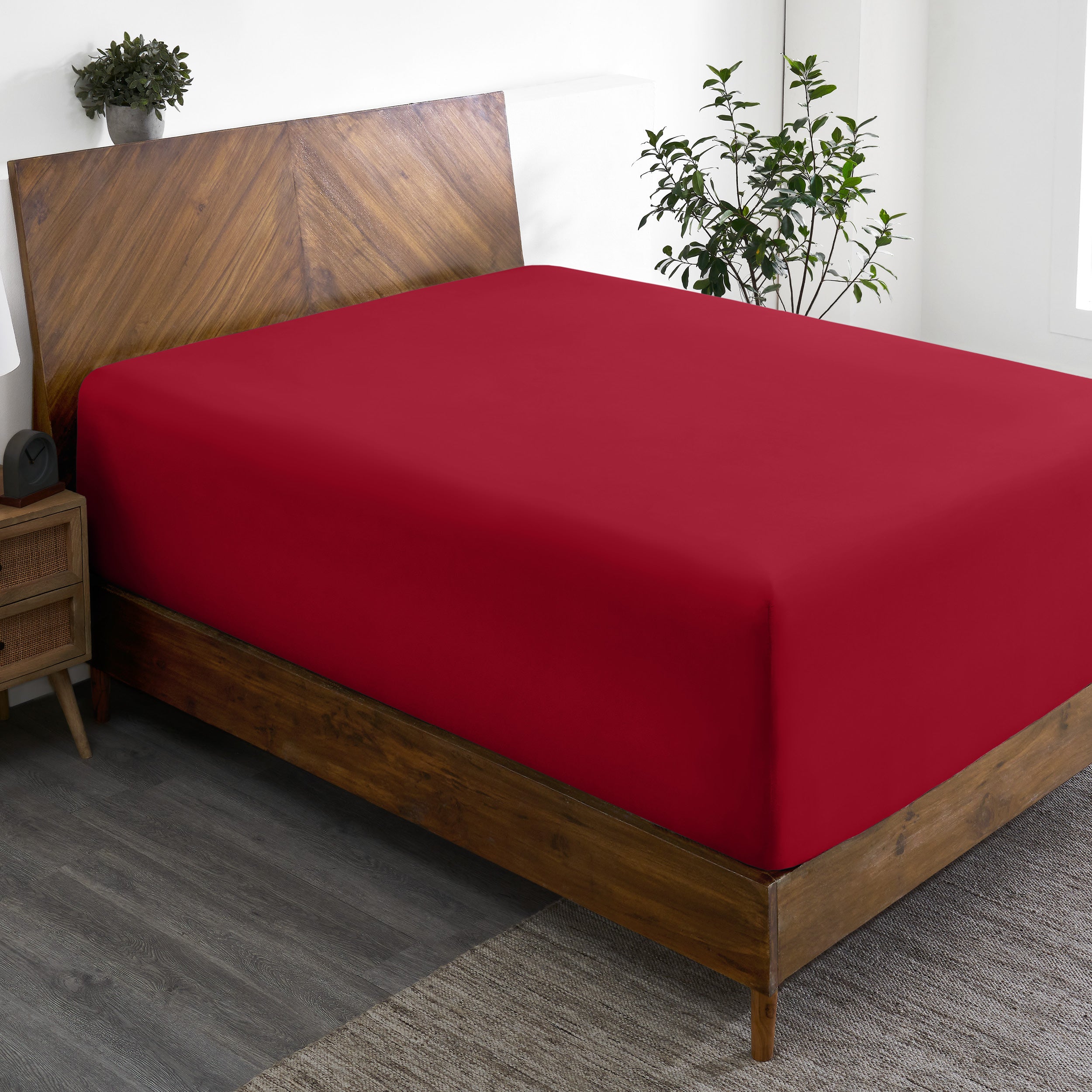 A wide corner view of a modern bed made with a microfiber fitted sheet on the mattress.