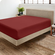 Corner view of a modern bed with a microfiber fitted sheet on the mattress.