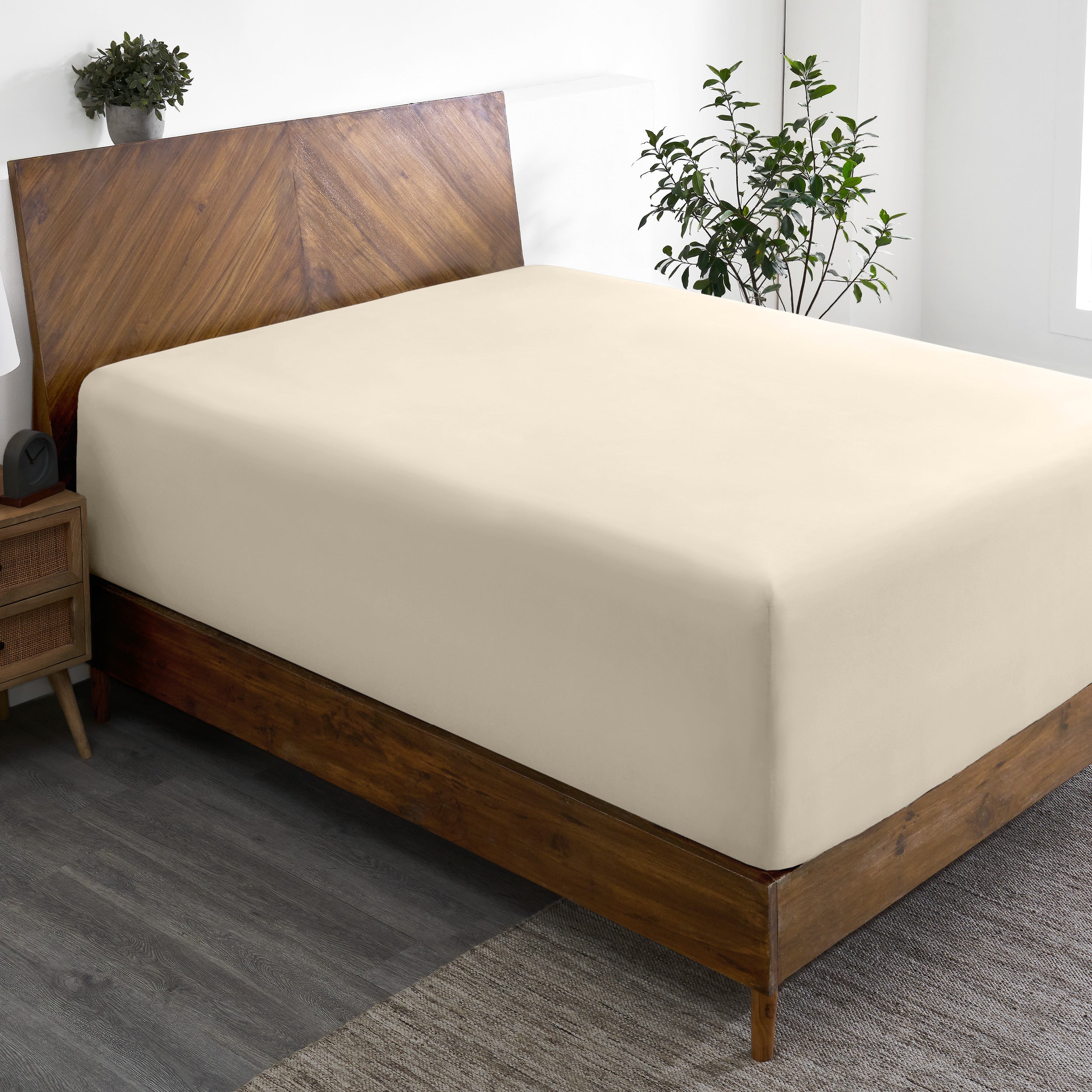 A wide corner view of a modern bed made with a microfiber fitted sheet on the mattress.