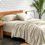 Microfiber sheets and matching pillowcases on a bed next to a large plant