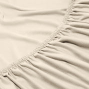Close-up of a fitted sheet with elastic edge on a bed.