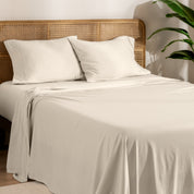 Organic jersey sheets and pillowcases on a bed with plants on the side in a bright and chill room scene.