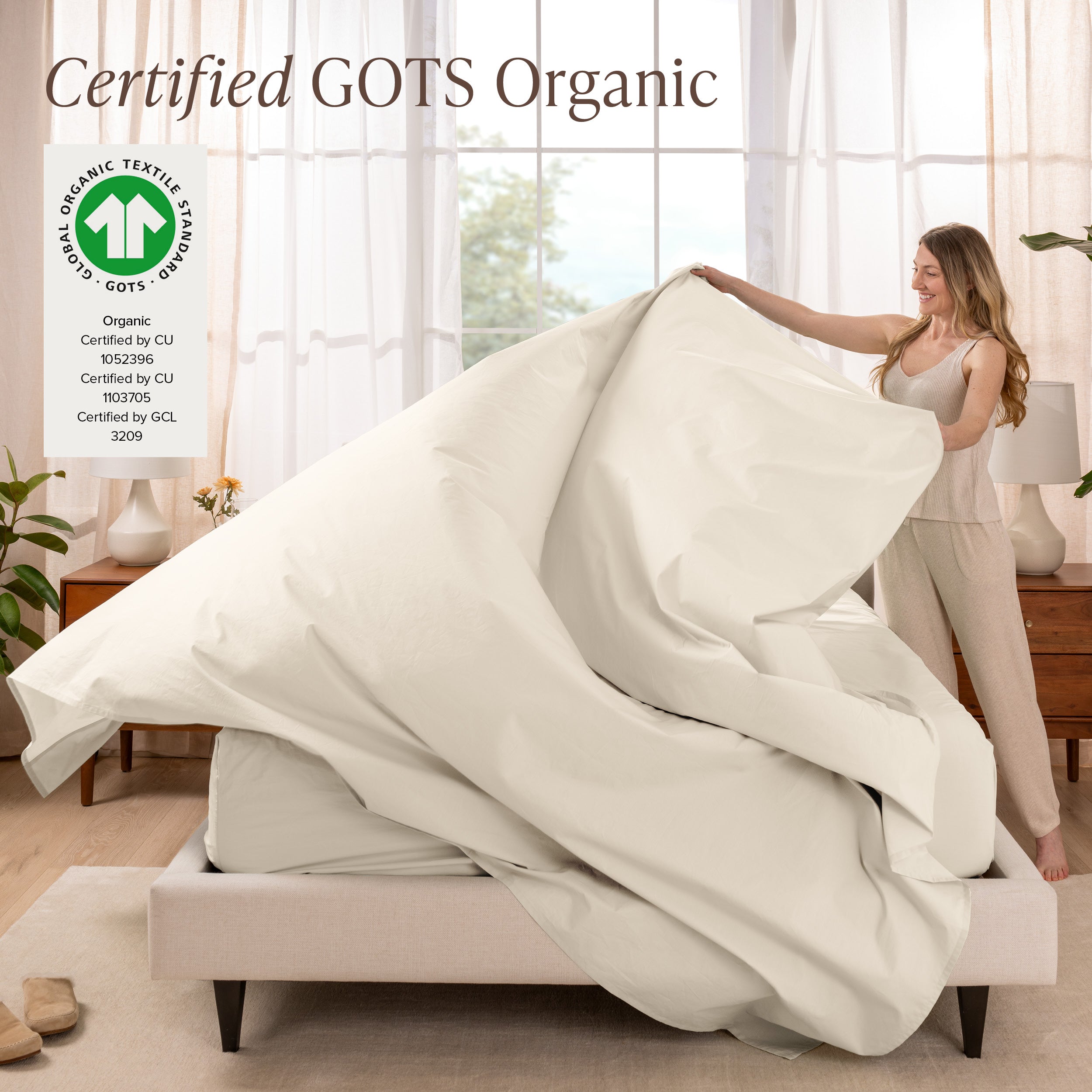 Woman putting bedding on a bed with GOTS Organic certification logo in the corner.