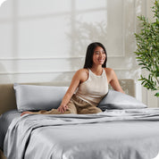A woman sitting on a bed made with satin sheets