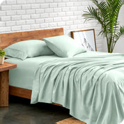 Microfiber sheets and matching pillowcases on a bed next to a large plant