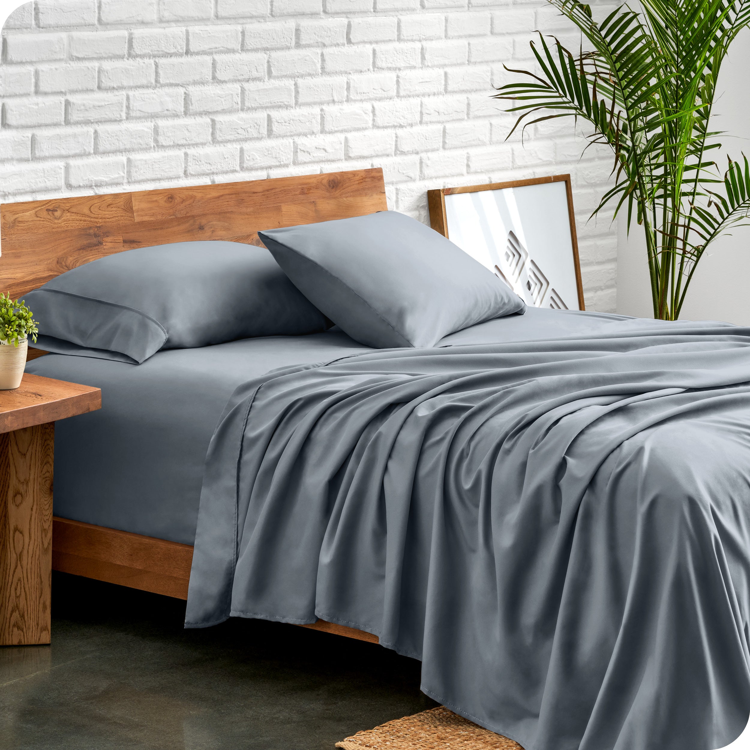 Microfiber sheets and matching pillowcases on a bed next to a large plant