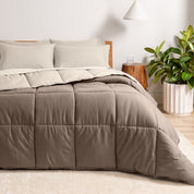 A wooden bed frame with a reversible comforter and sheet set on the mattress in a bright warm room.
