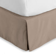 The corner of a bed skirt on a bed frame