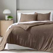 A comforter set on a bed in a bright modern room