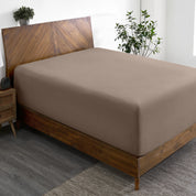 A wide corner view of a modern bed made with a microfiber fitted sheet on the mattress.