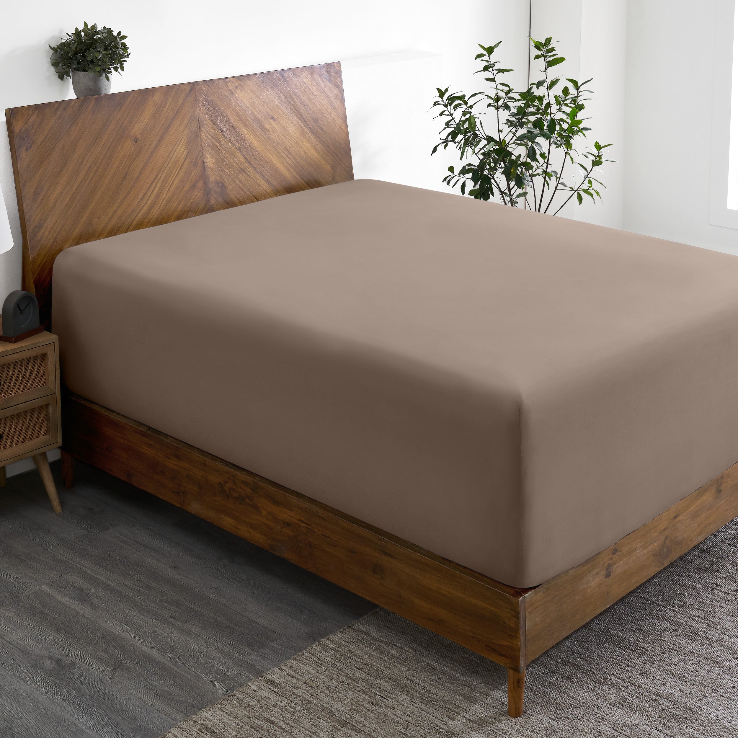 A wide corner view of a modern bed made with a microfiber fitted sheet on the mattress.