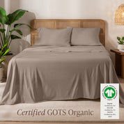 A bed in the middle of room with a set of Certified GOTS Organic Jersey Sheet Set on it.