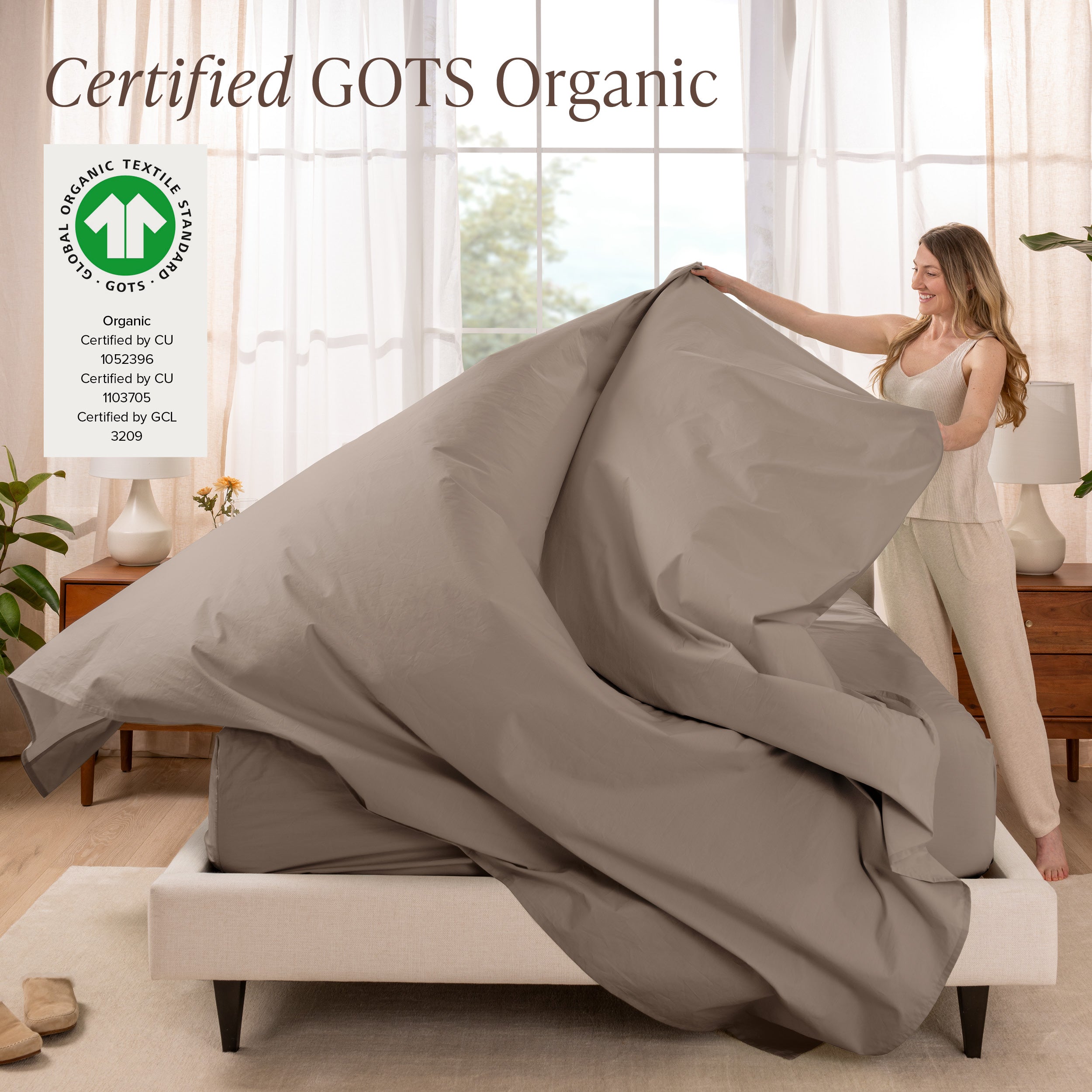 Woman putting bedding on a bed with GOTS Organic certification logo in the corner.