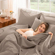 Woman lying in bed under percale sheets with a bright room setting