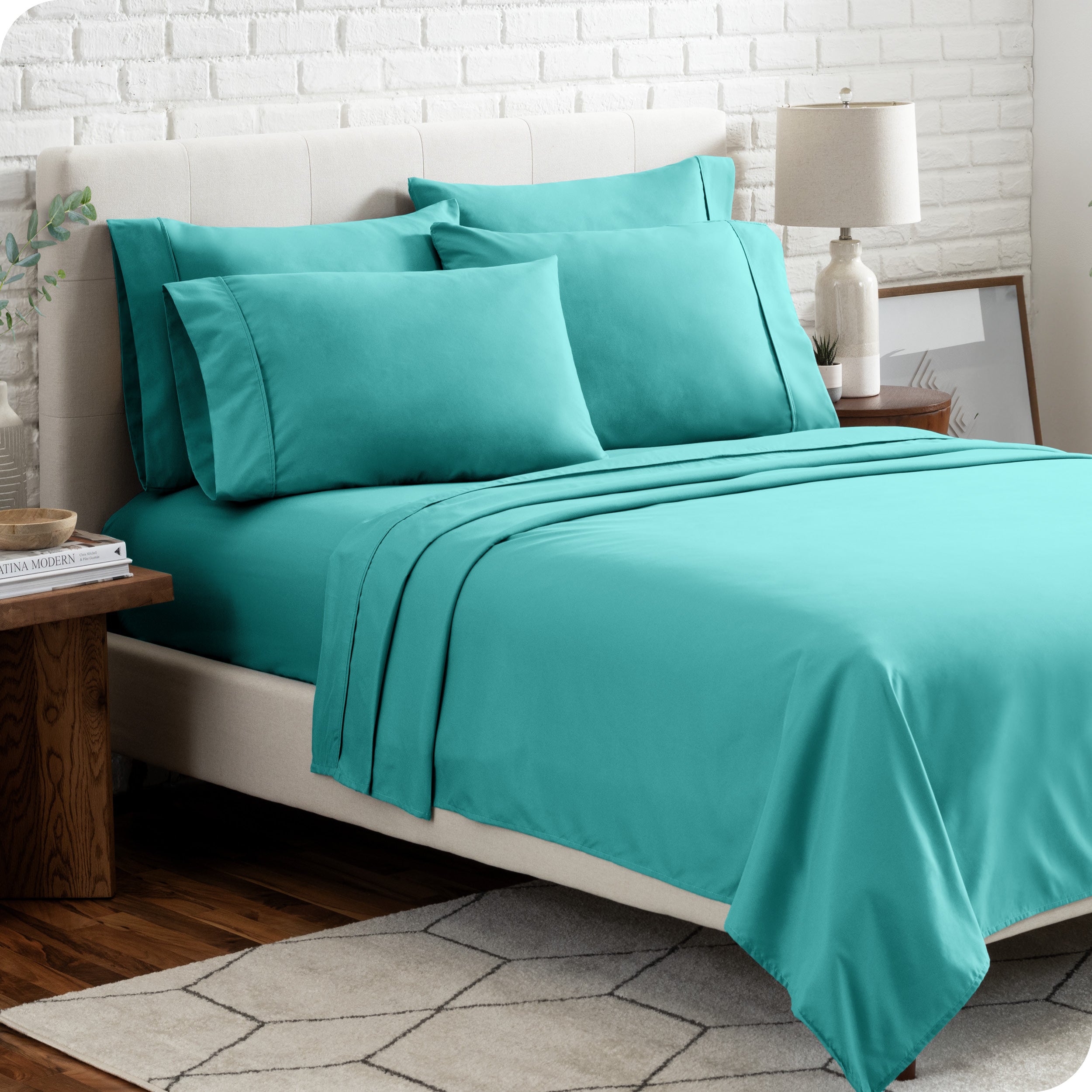 A bedroom setting with a bed made with the microfiber bed sheets and four pillows.