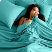 A smiling woman on a bed with a microfiber sheet over her