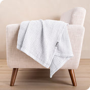 A cotton blanket on the arm of a chair