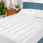 A mattress pad on a bed in a warm bright room.