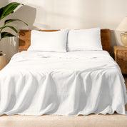 Bed with linen bedding and wooden headboard in a bedroom setting