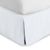The corner of a bed skirt on a bed frame