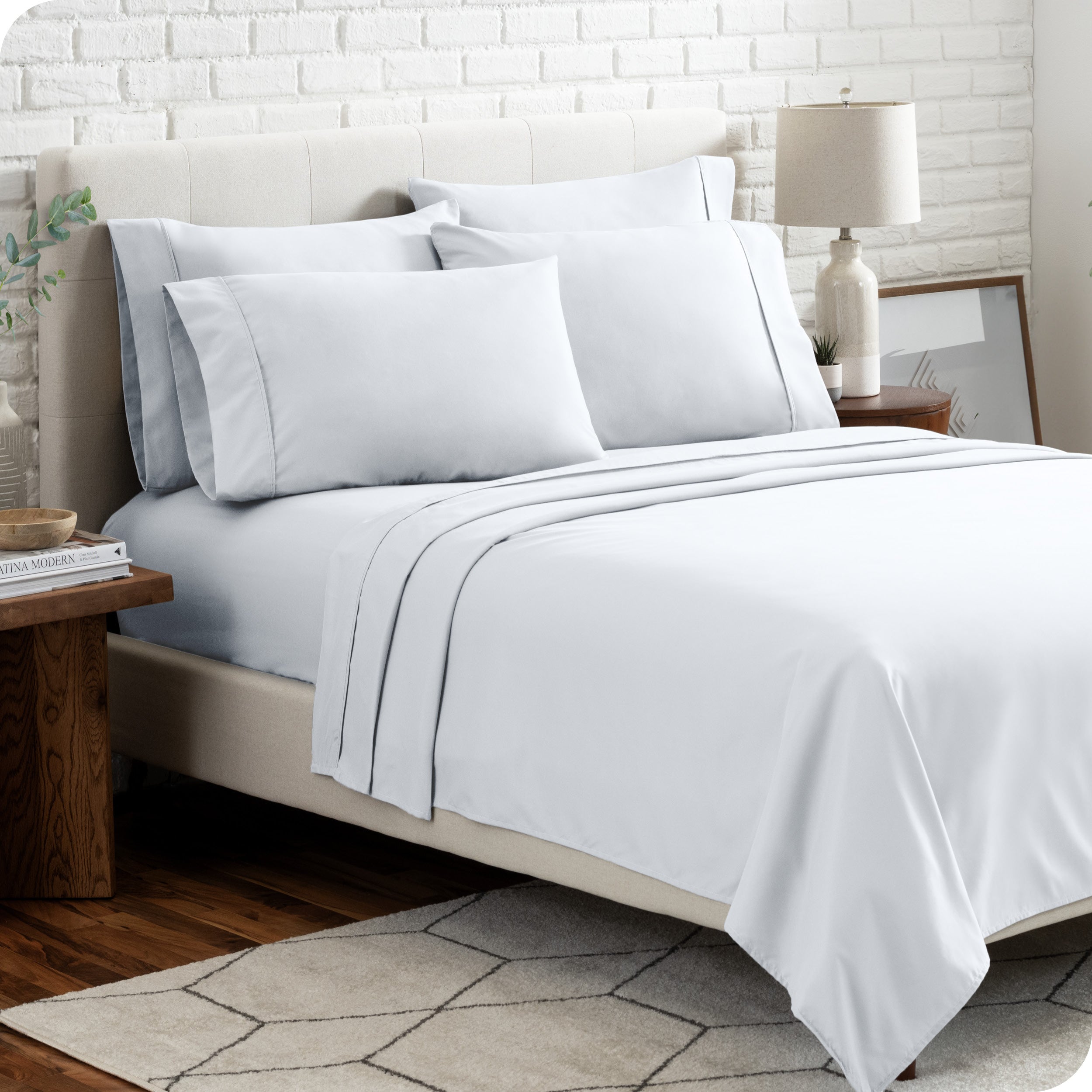 A bedroom setting with a bed made with the microfiber bed sheets and four pillows.