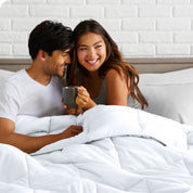 A couple sitting in bed with a comforter over them