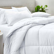 A side view of a modern bed with a comforter set and pillows on the bed