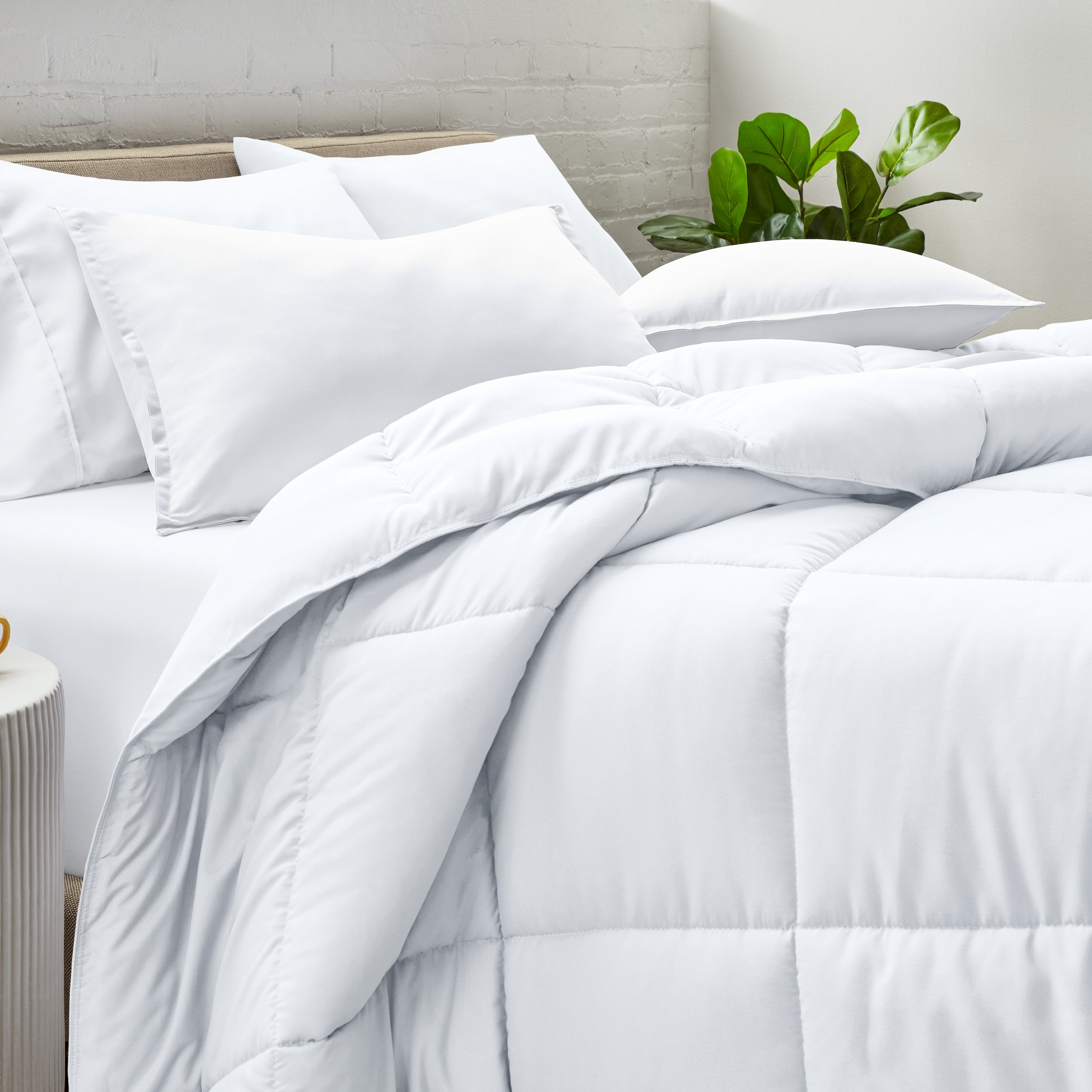 A side view of a modern bed with a comforter set and pillows on the bed