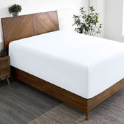 A wide corner view of a modern bed made with a microfiber fitted sheet on the mattress.