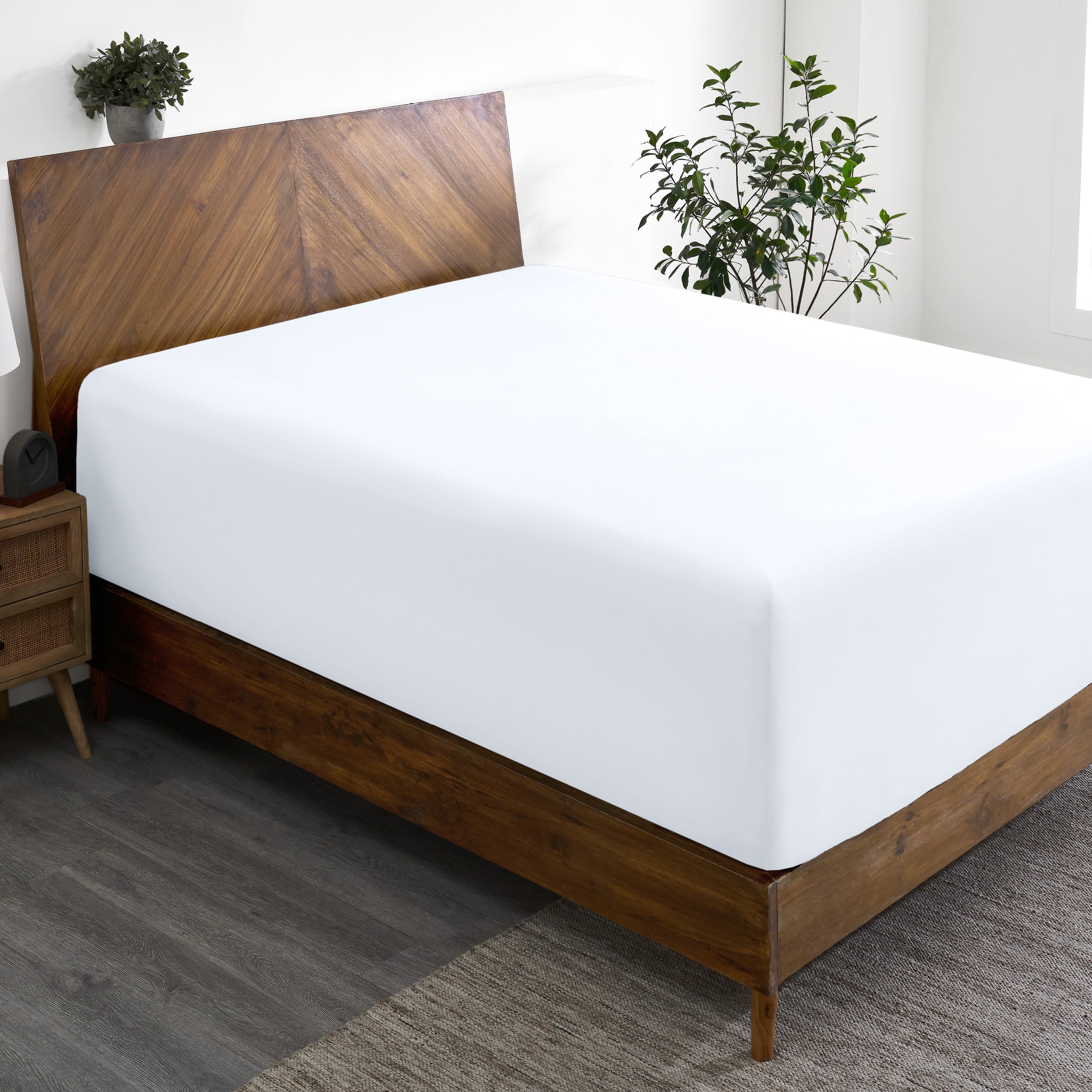 A wide corner view of a modern bed made with a microfiber fitted sheet on the mattress.