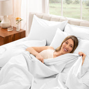 Woman lying in bed under percale sheets with a bright room setting
