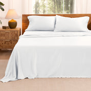 TENCEL™ sheet set on a bed with the flat sheet loosely draped over the top. The mattress is on a wooden bed frame.
