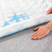 A hand is feeling the dry mattress underneath the wet mattress pad.